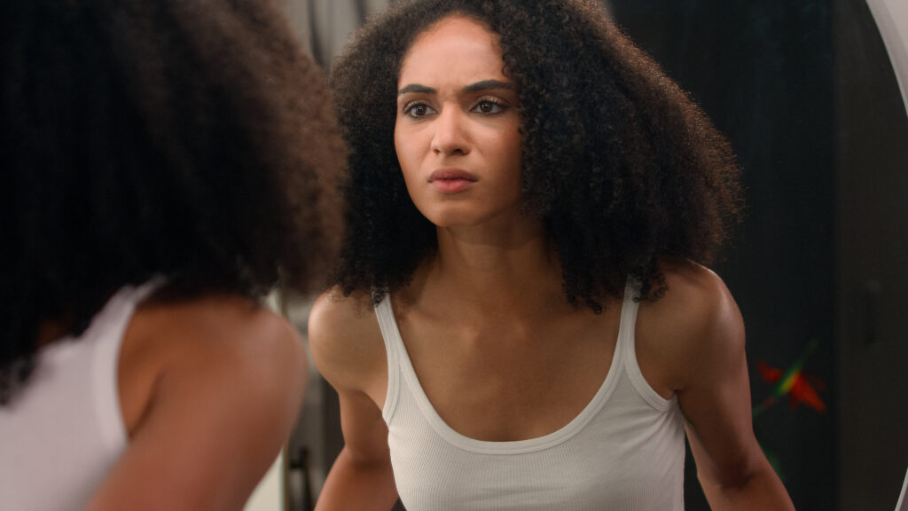 Worried young beautiful African American woman sad ethnic girl looking in mirror stressed about